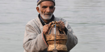 ٹھٹھرتی سردی کے بیچ جھیل ڈل میں معمر شہری کانگڑی سے گرمی کرتے ہوئے۔۔۔۔(فوٹو :ساحل میر)